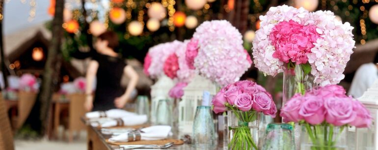 Duża sala weselna na której znajdują się różowe kwiaty